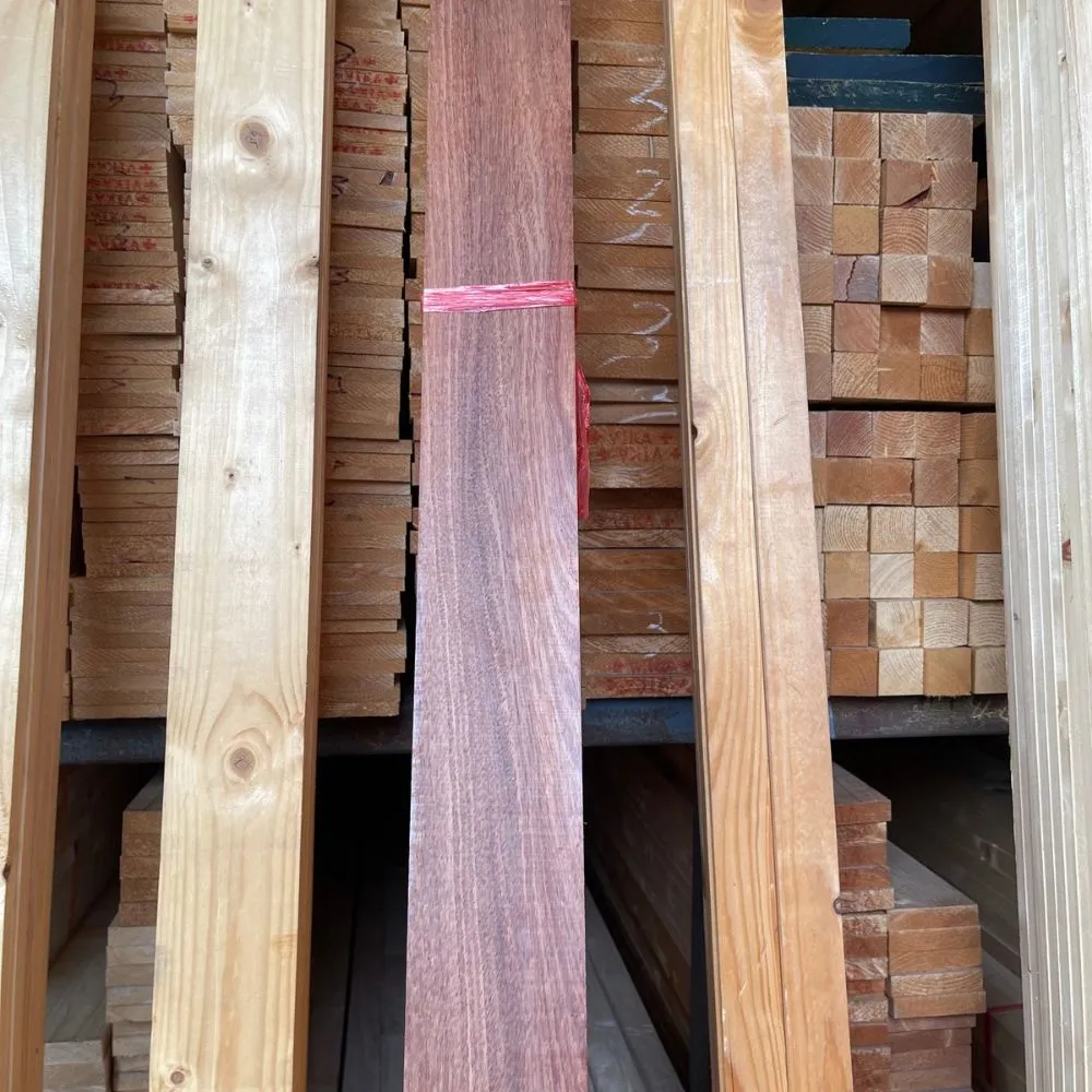 red-hardwood-timber-stacked-lumber ภาพถ่ายไม้แดงแปรรูปจริง แสดงสีเนื้อไม้โทนน้ำตาลแดงและลวดลายไม้ธรรมชาติ